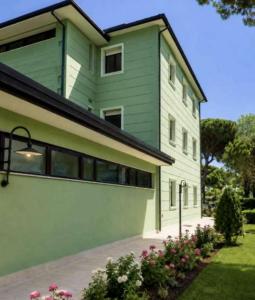 a green and white building with flowers in front of it at Hotel Venus in Milano Marittima