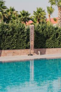a sign next to a swimming pool with palm trees at Stillo Business Hotel & Spa in Aliağa