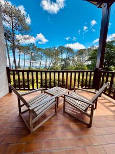 two wooden benches sitting on a deck with a view of the water at Duplex T3 2 étoiles bord de lac 65mcarrés in Biscarrosse