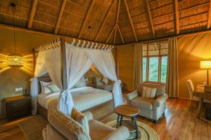 a bedroom with a canopy bed and a table and chairs at Kidepo Wilderness Lodge in Loitanit