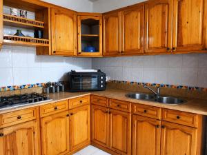 a kitchen with wooden cabinets and a sink and a microwave at Plage al amin eden in Fnidek