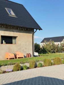a house with two chairs and a table in front of it at Dom na wsi in Chmielno