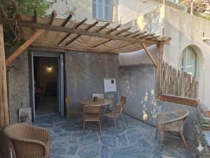 a patio with a table and chairs and a wooden pergola at Maison Milani Centuri in Centuri