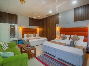 a hotel room with two beds and a green couch at Hotel Amar in Mussoorie