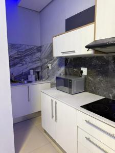 a kitchen with white cabinets and a microwave at Deluxe Nest - Windhoek in Windhoek