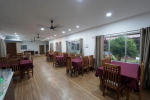 a dining room with purple tables and chairs and windows at Raj Garden Resort in Guwahati
