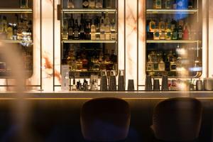 two chairs in front of a bar with bottles of alcohol at The Cloud One Wien-Staatsoper in Vienna