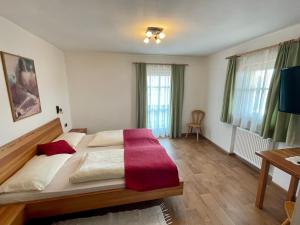 a bedroom with a large bed with a red blanket on it at Da Kathi in San Candido
