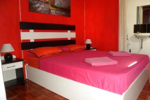 a red bedroom with a large bed with pink sheets at Chez Mimi in Rodrigues Island +17 photos