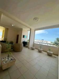 a large living room with potted plants and a large window at Appartement meublé service in Cotonou +4 photos