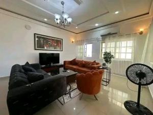 a living room with a leather couch and a tv at Appartement meublé service in Cotonou