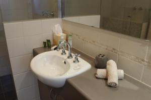 
a bathroom with a sink, mirror, soap dispenser and towel rack at Meelup Bed & Breakfast in Dunsborough
