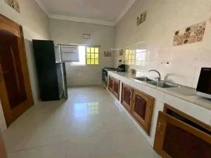 a large kitchen with a sink and a refrigerator at Appartement meublé service in Cotonou