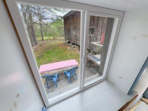 a window view of a picnic table and a barn at The ShackHilton at Dancing Light Farm in Bridgton