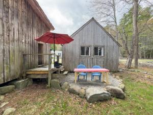 a picnic table with two chairs and a red umbrella at The ShackHilton at Dancing Light Farm in Bridgton +17 photos