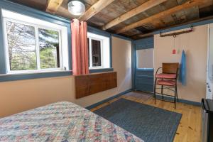 a bedroom with a bed and a window and a chair at The ShackHilton at Dancing Light Farm in Bridgton