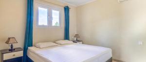 a bedroom with a bed with blue trim and a window at Wayaca Mini Resort in Willemstad