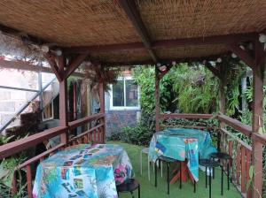 a patio with two tables and chairs on a porch at La baie rose in Sainte-Rose