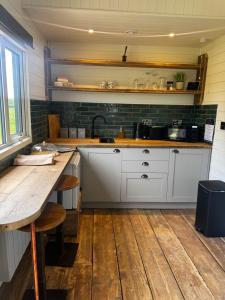 a kitchen with white cabinets and a wooden table at Lakeside Shepard's Hut 'Sanderling' in Bishampton +9 photos