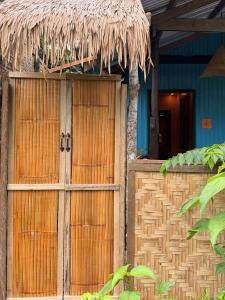 a wooden gate to a house with a thatch roof at Casa Paco Siargao in Catagnan