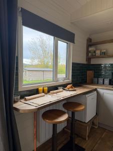 a kitchen with a counter with two stools and a window at Lakeside Shepard's Hut 'Sanderling' in Bishampton