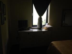 a bedroom with a window and a dresser with a television at Podere Caselina b&b in Camugnano