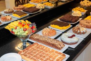 a buffet filled with different types of cakes and pastries at Hotel Évora by Rede Sagres in Florianópolis
