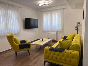 a living room with a yellow couch and two chairs at Apartman Quattro 2 in Međugorje