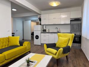 a living room with yellow chairs and a kitchen at Apartman Quattro 2 in Međugorje
