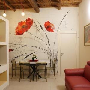a dining room with a table with red flowers on the wall at L'Abbraccio in Tivoli