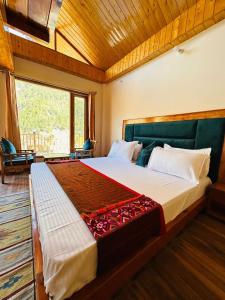 a bedroom with a large bed with a large window at Above & Beyond - Tirthan in Banjār +33 photos