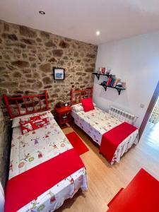 a bedroom with two beds and a stone wall at Casa Rural A Redondiña in Lamas