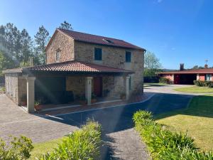 a brick house with a garage and a driveway at Casa Rural A Redondiña in Lamas