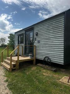 a tiny house with a porch and a deck at Lakeside Shepard's Hut 'Sanderling' in Bishampton