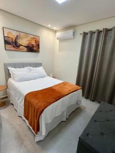 a bedroom with a bed with a orange blanket on it at Casa Nova, 2 quartos, 1 Ar-Cond, 1 Banheiro, Garagem 4,30m in Montes Claros