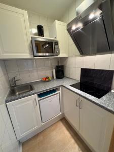 a kitchen with white cabinets and a sink and a microwave at Ostseekoje Koje 4 in Süssau
