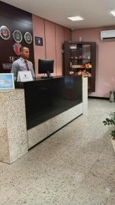 a man is sitting at a counter in a store at Steel Valley Economic Hotel in Ipatinga