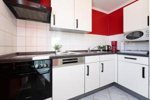 a kitchen with white cabinets and a black stove at Dorfstraße 28 Seeadler in Klausdorf