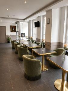 a waiting room with tables and chairs and a television at Hôtel Belle Fontainebleau in Fontainebleau