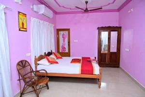 a bedroom with purple walls and a bed and a chair at Harbour villa 1 in Trivandrum
