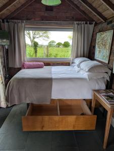 a large bed in a room with a window at La'al Cabin, tiny home, unique space Eden Valley Cumbria in Brampton
