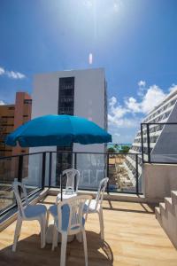 a table and chairs on a balcony with a blue umbrella at Hotel Kazullo in Maceió