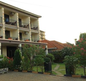 a building with balconies and a courtyard with trees and flowers at Hotel Casabella in Entebbe
