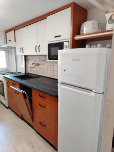 a kitchen with a white refrigerator and wooden cabinets at Prokop Vendégház in Tolcsva