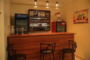 a bar with three chairs and a counter with wine glasses at Hotel Casabella in Entebbe