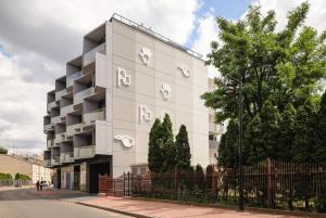 a white building with the letter r on it at Neon Apartments Centrum in Częstochowa