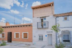a white building with a balcony next to a brick building at Casa Da Rita in Matapozuelos