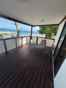 a wooden deck with two chairs and the beach at Ohotu Lodge in Rangiroa +1 photo