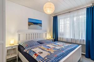 a bedroom with a bed and a window with blue curtains at An't Fischerspad in Wangerland