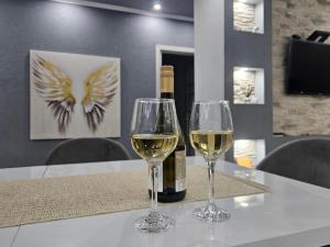 two glasses of white wine on a table with a bottle of wine at Aranyszárny Apartman in Gyula +17 photos